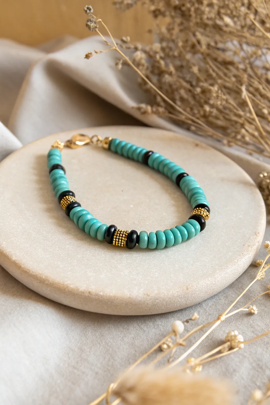 Dainty cowgirl bracelet: turquoise heishis with black and gold seed bead spacers on warm tan.