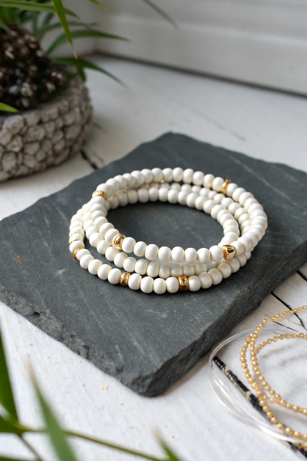 Minimal monochrome heishi stack in white with a single gold spacer bracelet for chic contrast.