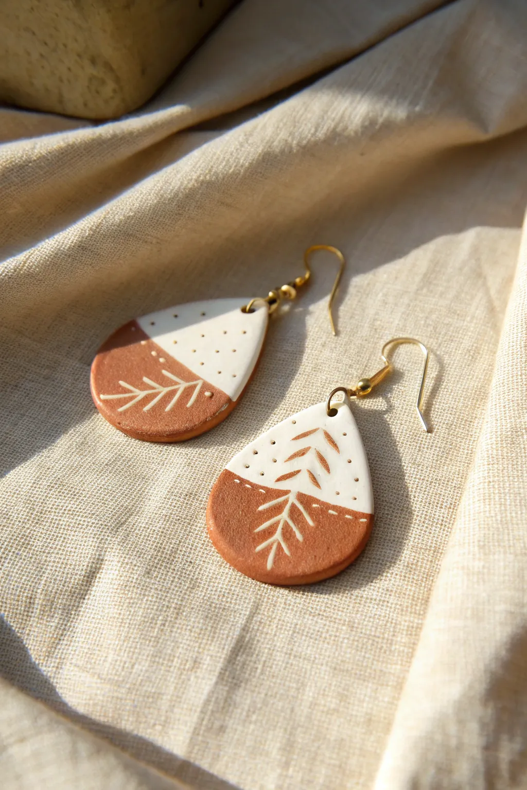 Sgraffito teardrop clay earring with clean scratch lines and a soft satin finish on linen.