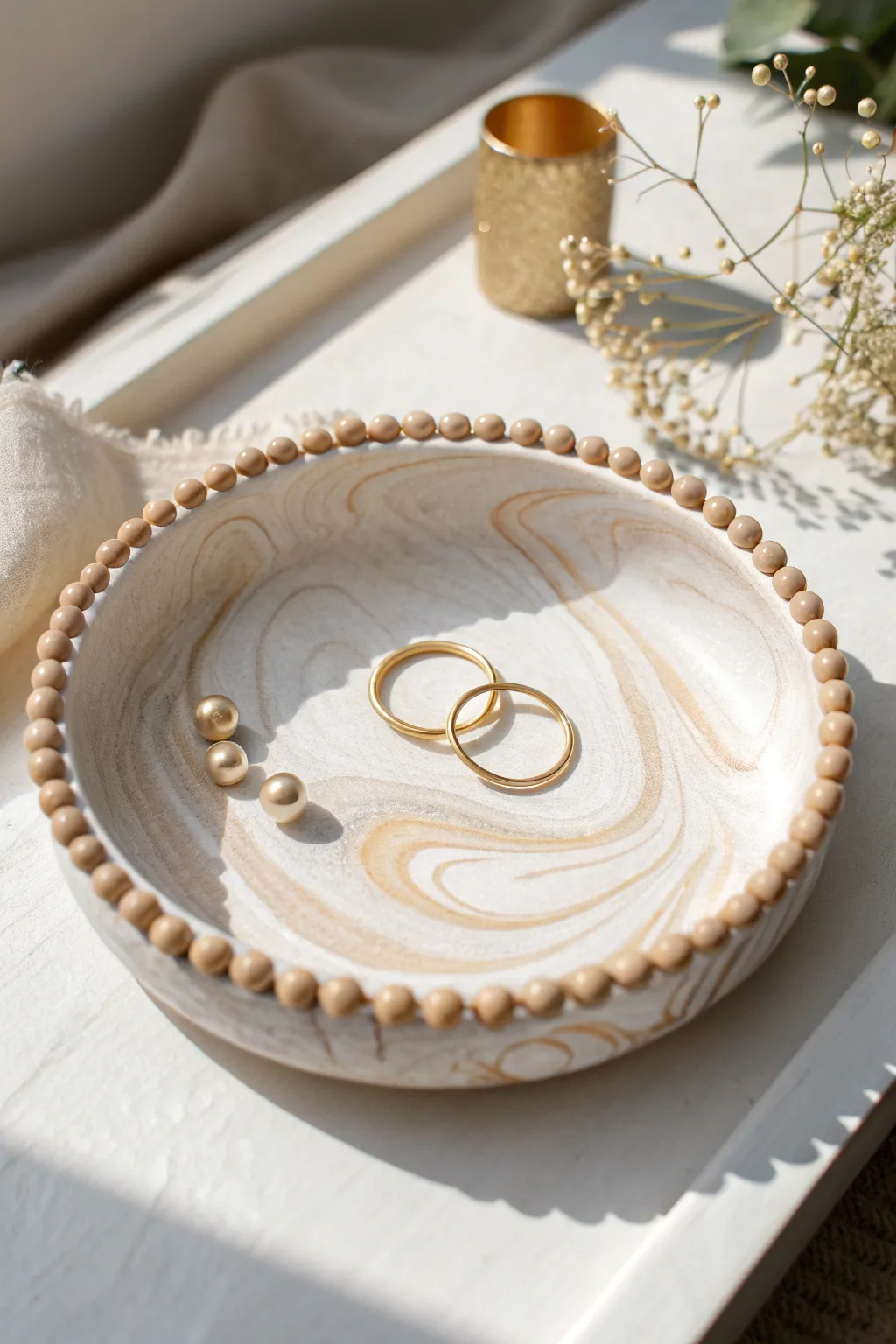 Marbled air dry clay trinket dish with a sweet beaded rim, styled with simple gold jewelry.