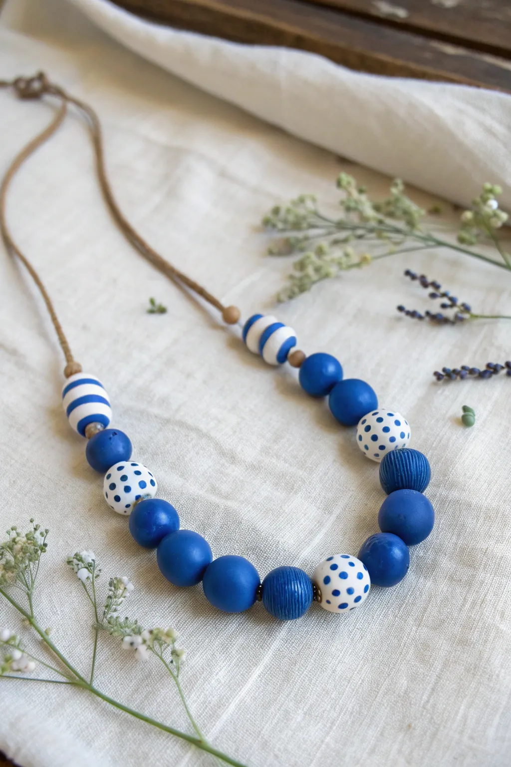 Simple blue clay bead set with stripes and dots, styled in a minimal flat lay