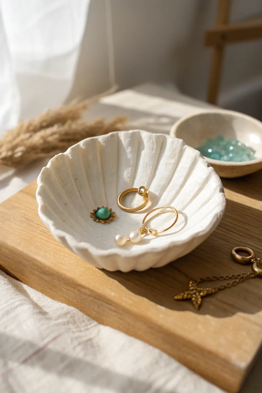 Creamy pearl seashell trinket bowl styled with tiny earrings and sea-glass accents