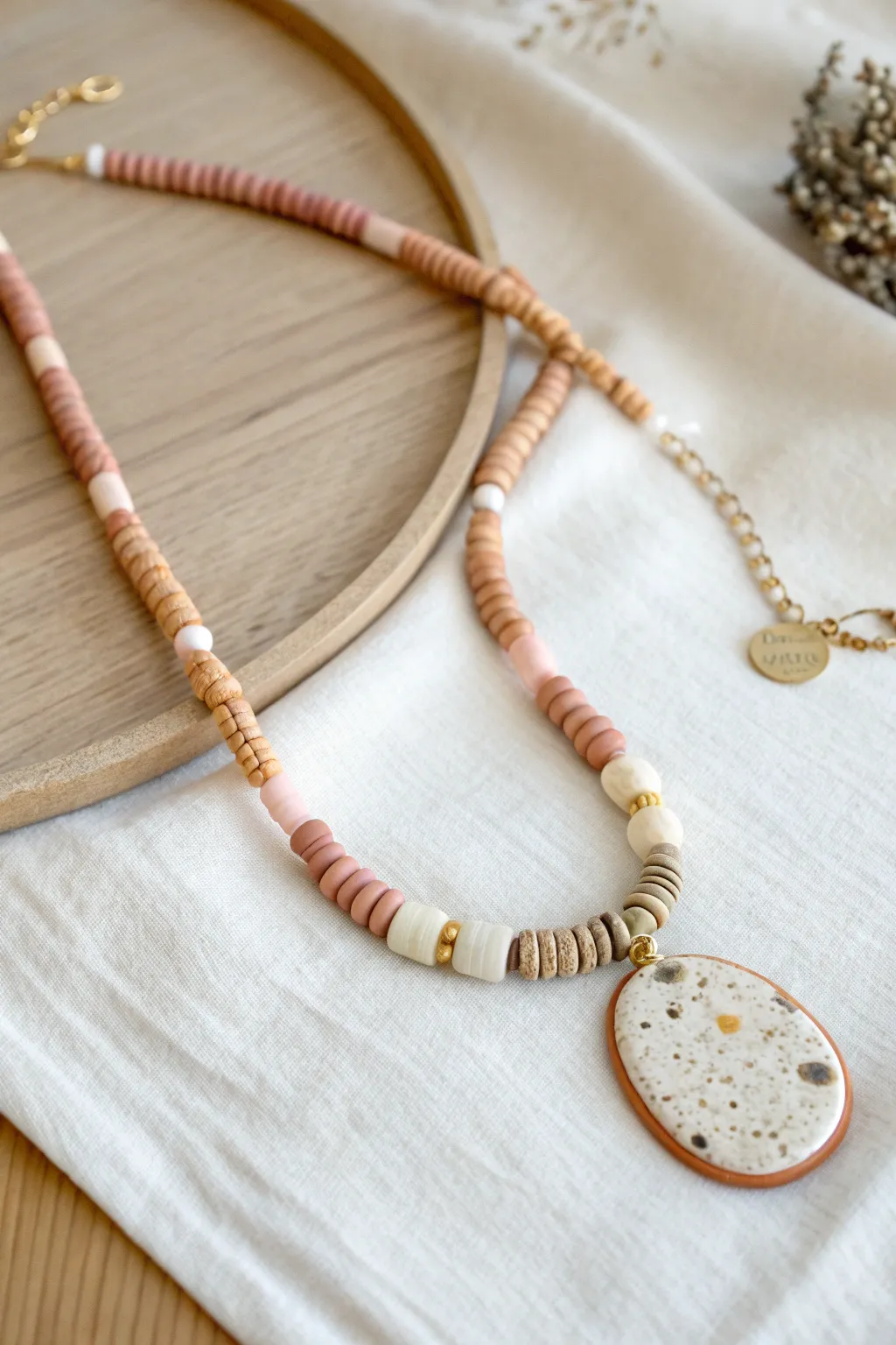 Centered clay pendant with a beaded bail, framed by soft heishi beads for a clean boho look.