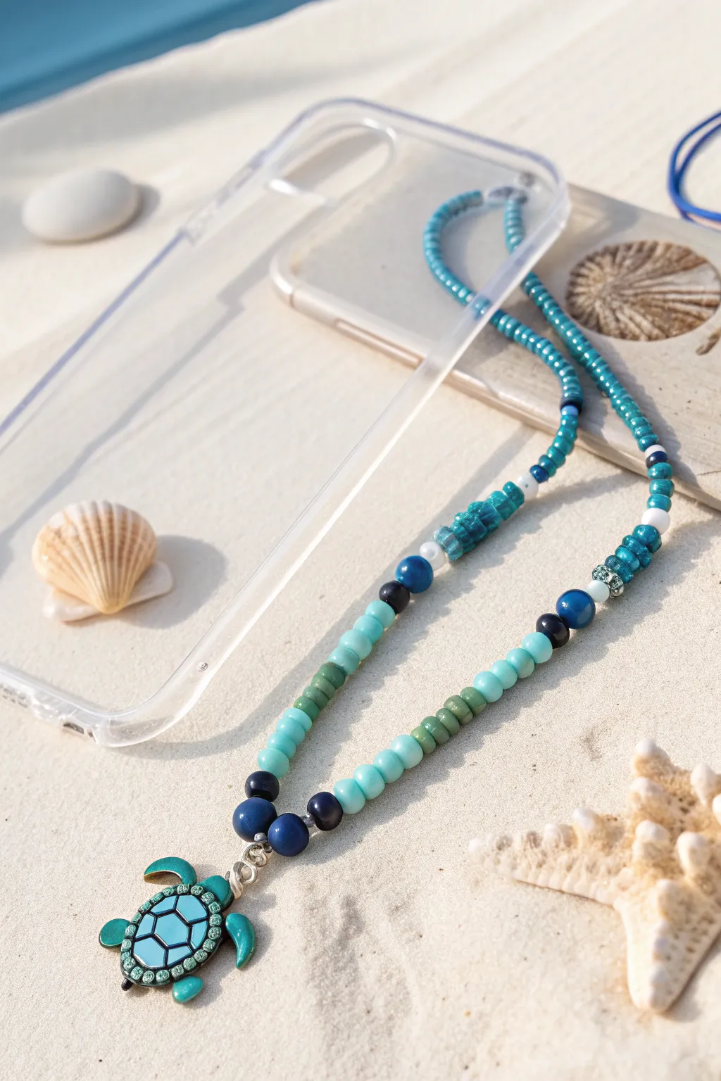 Ocean-blue heishi bead phone charm with a tiny turtle centerpiece, minimal and beachy chic