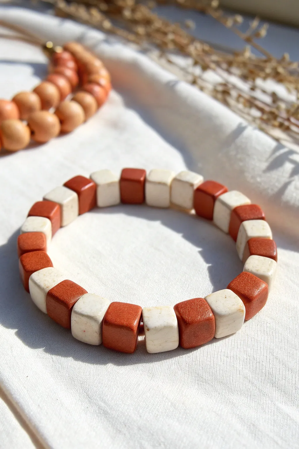 Bold checkerboard clay bead bracelet in terracotta and cream, minimalist flat-lay beauty