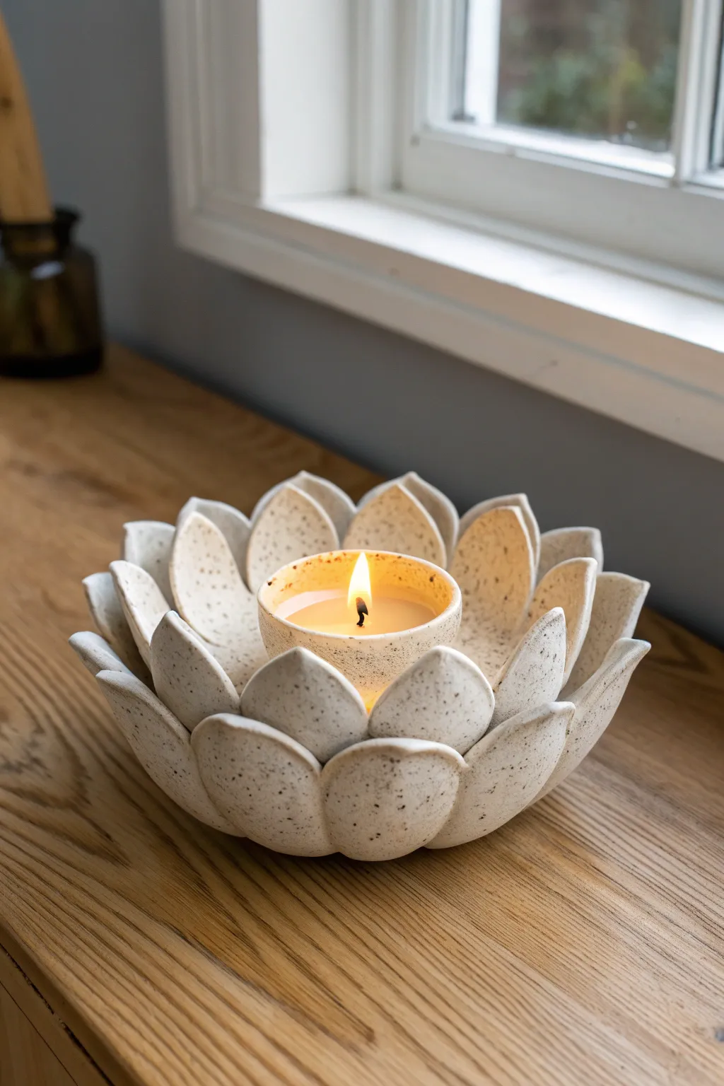 A scalloped lotus clay tea light bowl, softly glowing, minimalist Scandinavian style with boho warmth
