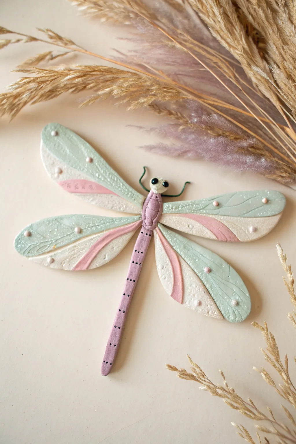 Dainty pastel clay damselfly with airy wings for a minimalist, boho-inspired shelf accent