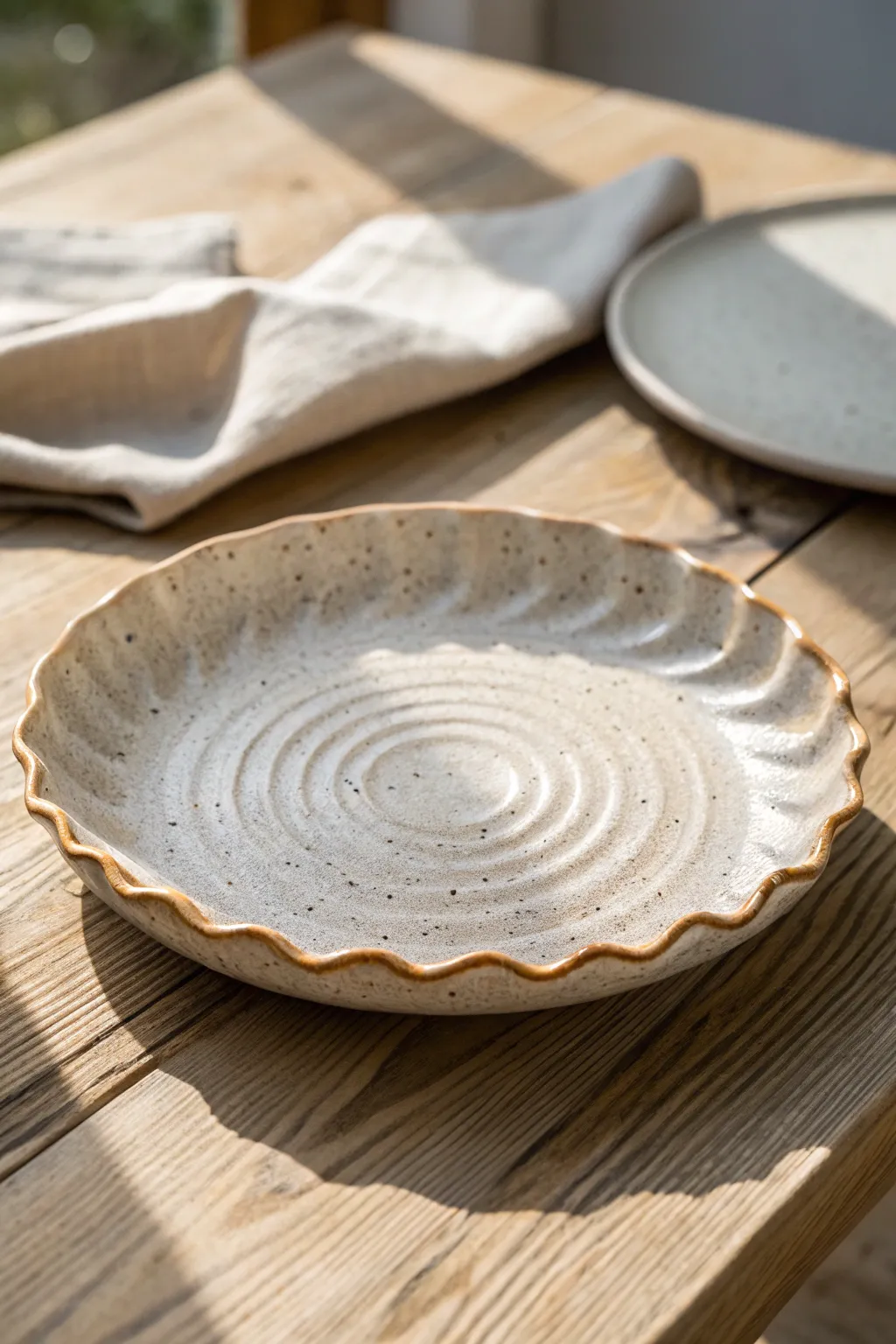 Wonky chic wavy clay plate with soft ripples, styled simply on light oak for calm contrast.