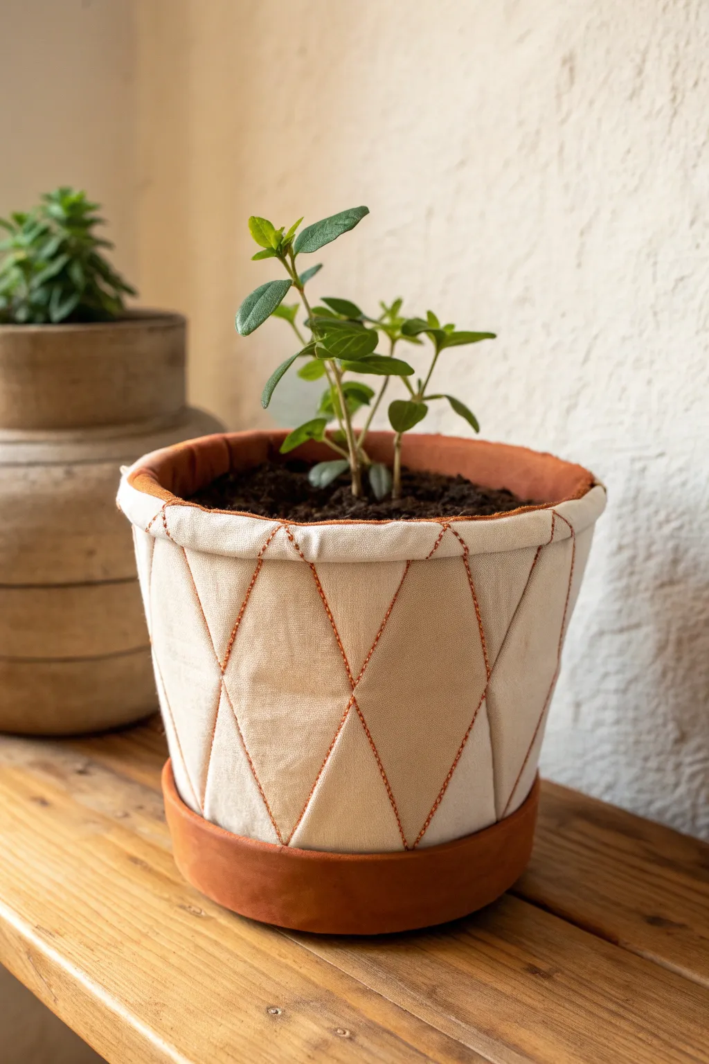 Cozy clay pot with linen-wrapped panels, warm light, and a leafy plant for soft texture.