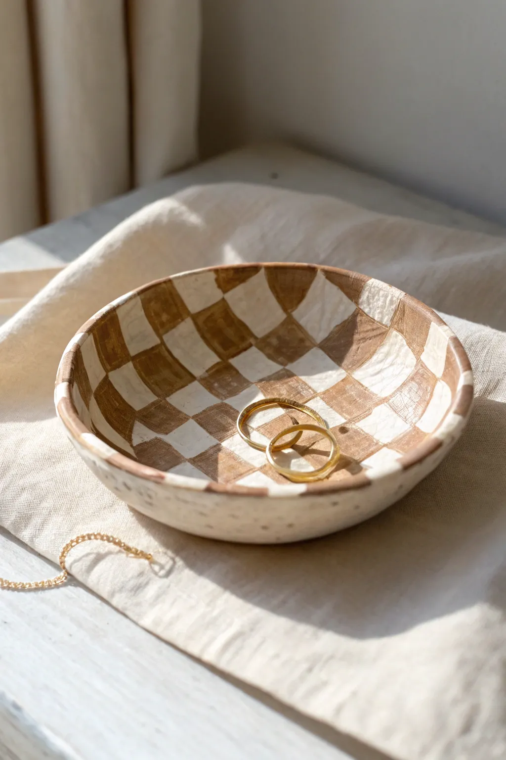Neutral checkerboard clay arch dish styled with simple jewelry for a clean boho-minimal look