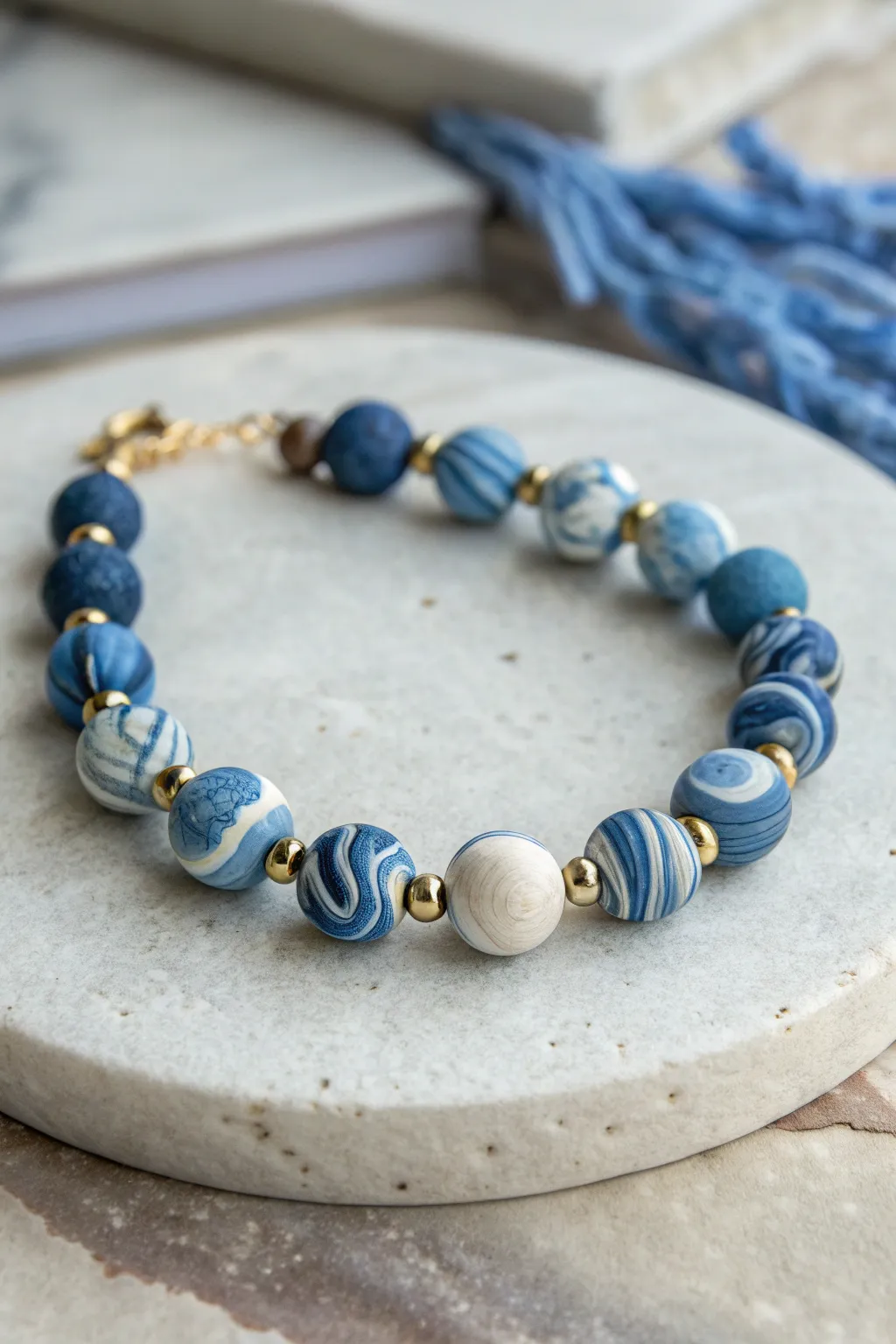 Blue marble swirl focal beads with simple heishi accents on a clean concrete backdrop