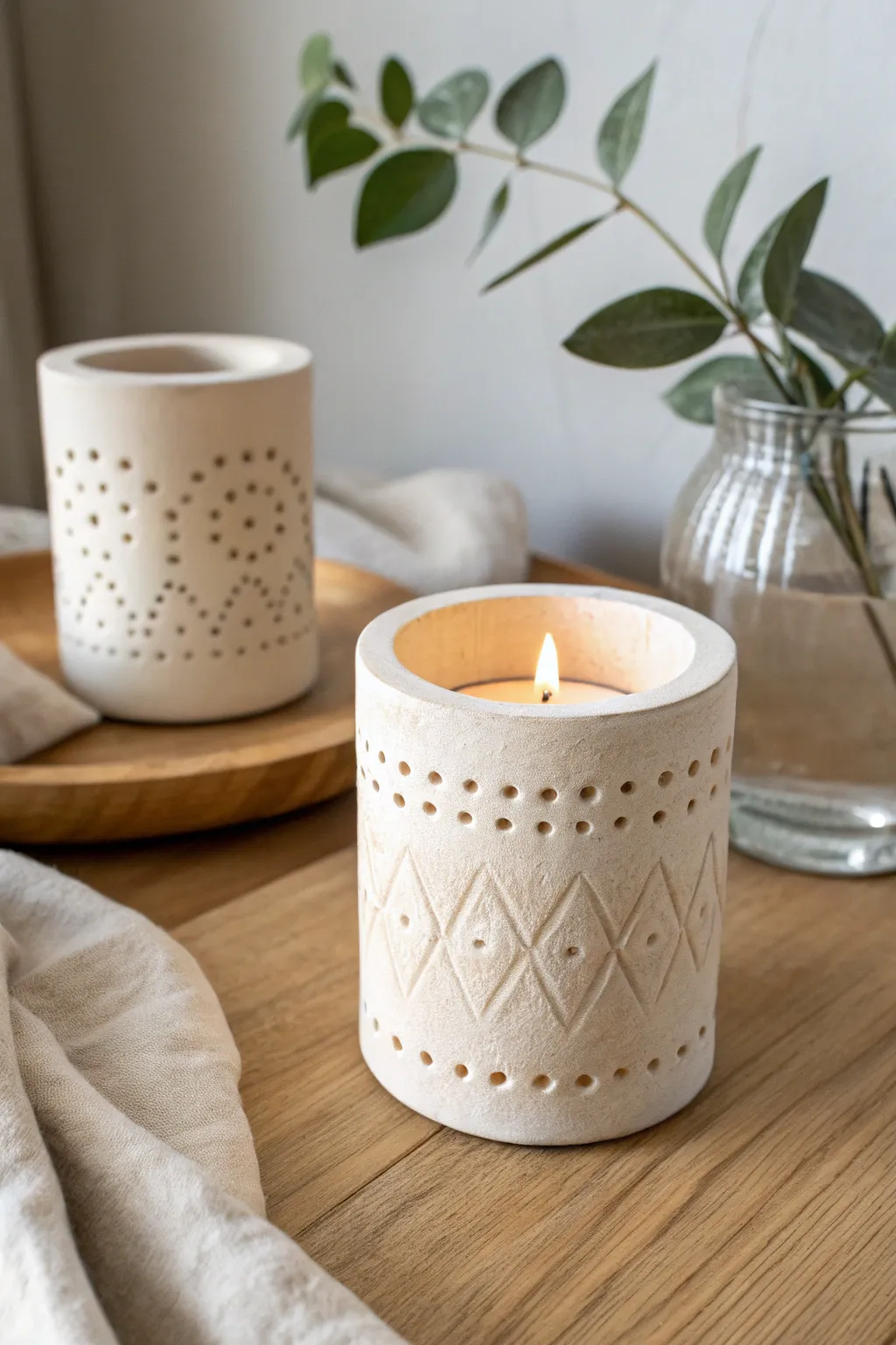 Softly textured DIY clay tea light holder in matte cream, minimal styling, warm glow.