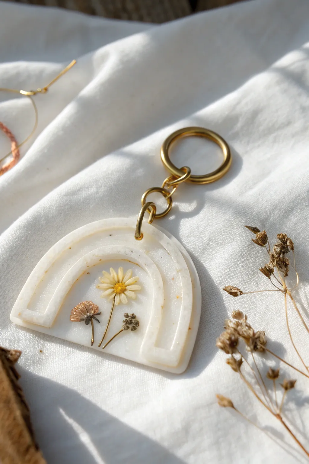 Pressed-flower window keychain in soft translucent clay with clean edges and simple gold hardware.