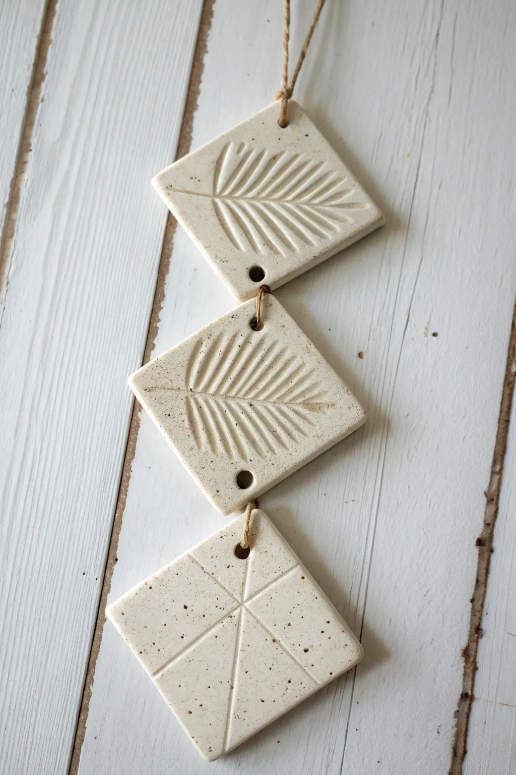 Three textured slab tiles on jute cord bring soft boho warmth to a minimalist wall.