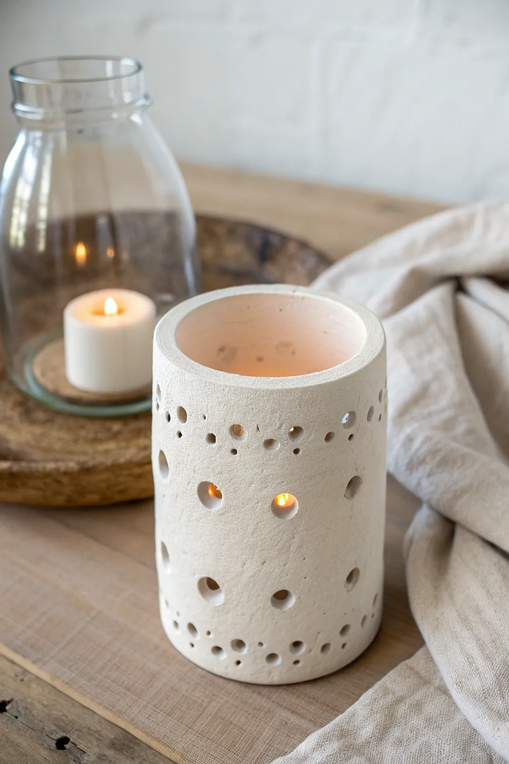 Minimal clay lantern sleeve over glass insert, warm glow and simple Scandinavian charm.
