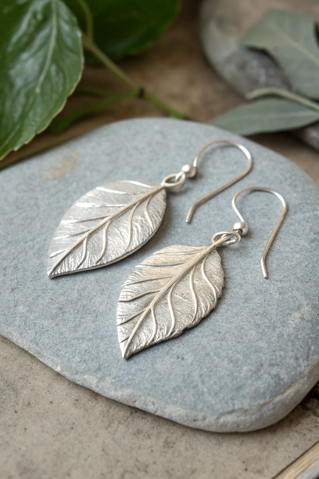 Fold-formed leaf earrings in silver metal clay, minimalist boho beauty styled on natural stone
