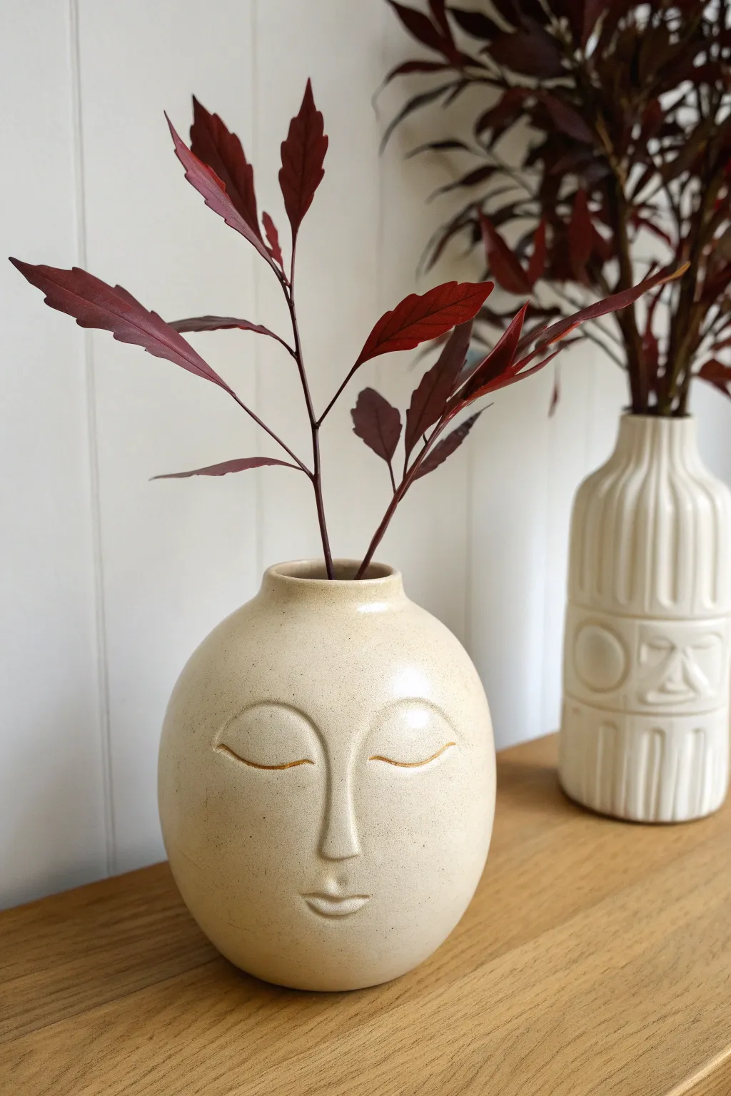 Minimal face vase in satin neutral, styled with a single bold stem for calm modern charm.