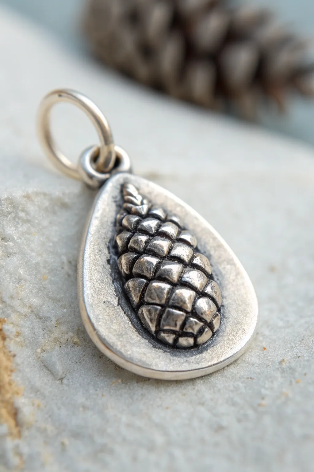 Pinecone-textured silver clay charm with soft patina, minimalist styling and warm light.