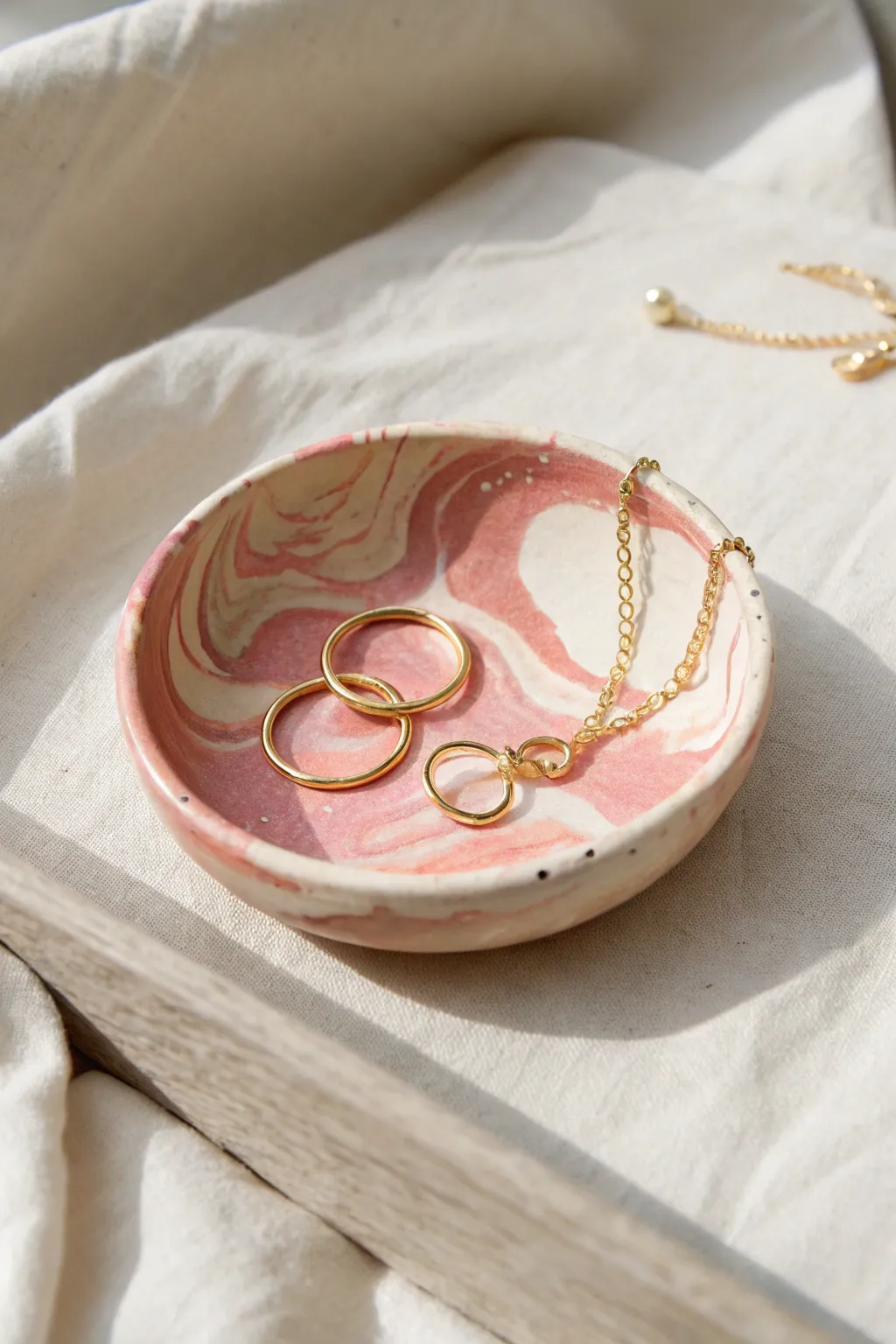 Blush marbled clay jewelry dish styled with delicate gold pieces on a calm minimalist backdrop