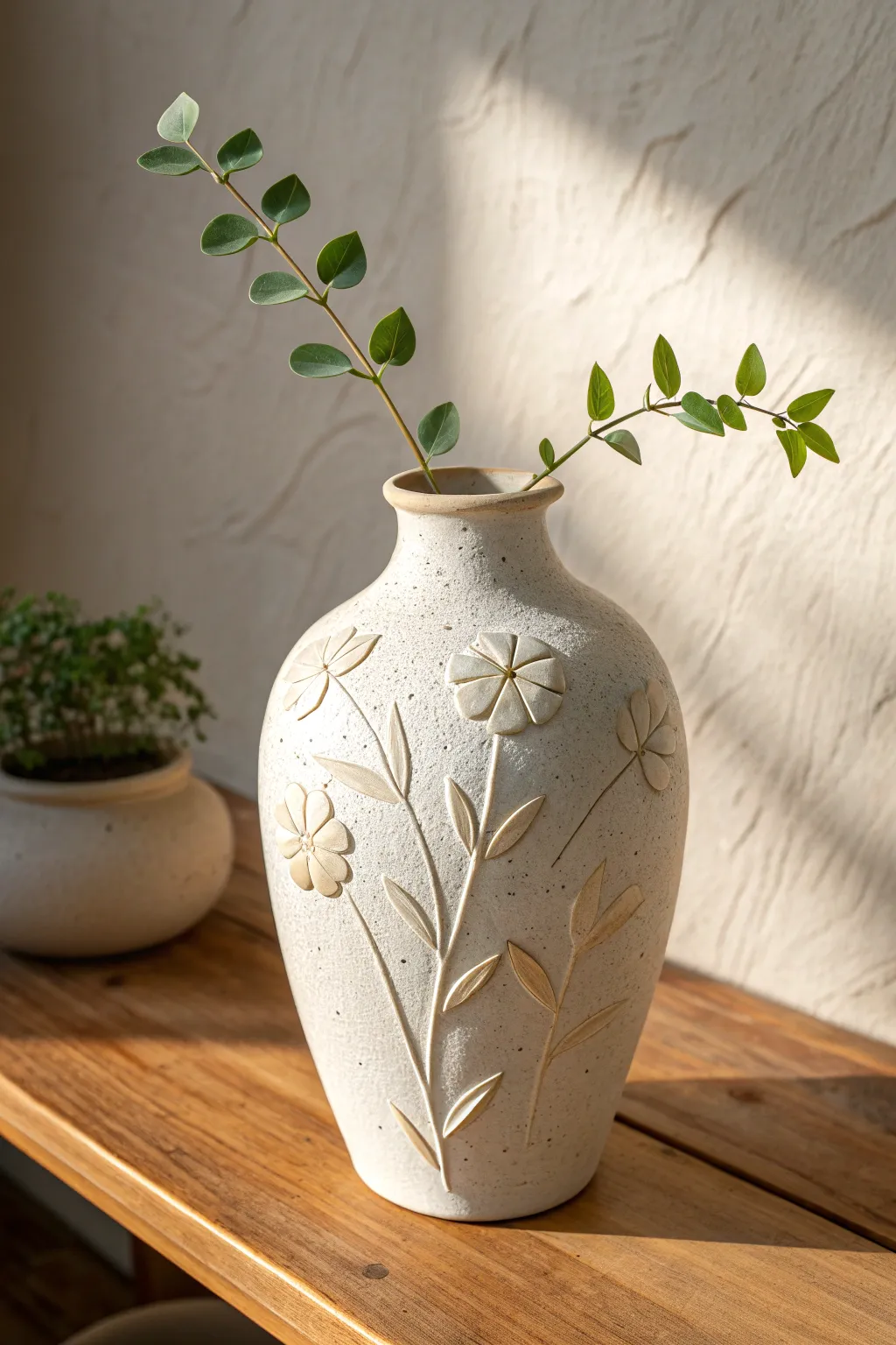 Minimalist ceramic vase with raised floral appliqué, matte glaze, cozy Nordic styling.