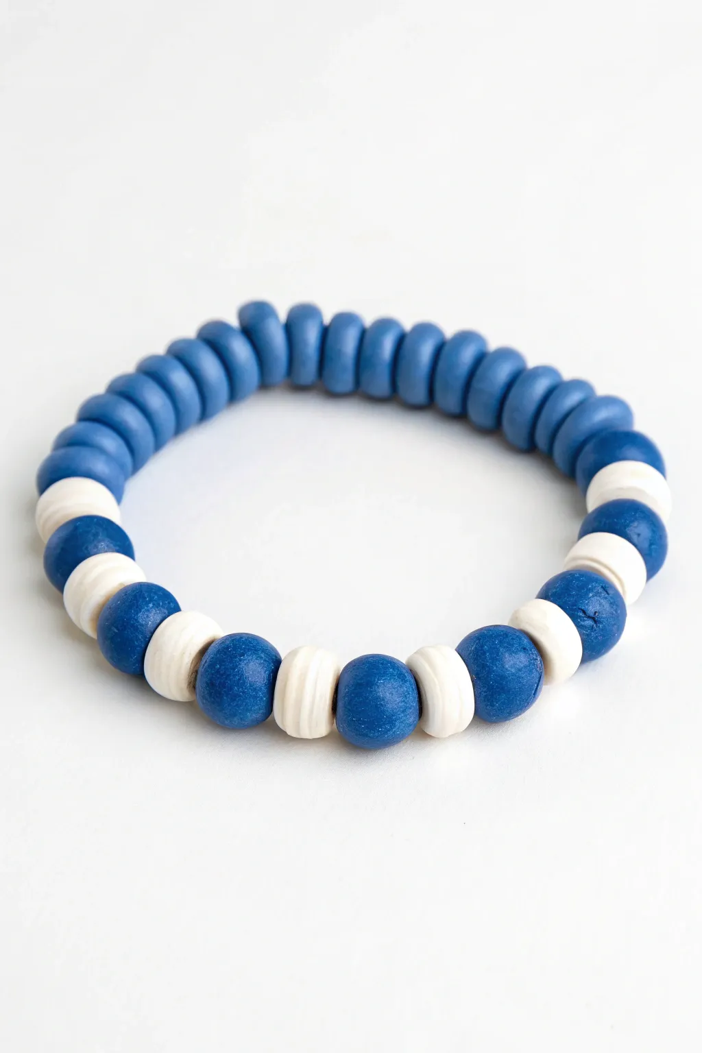 Blue and white clay bead bracelet with a flowing wave pattern, simple, calming, handmade charm.