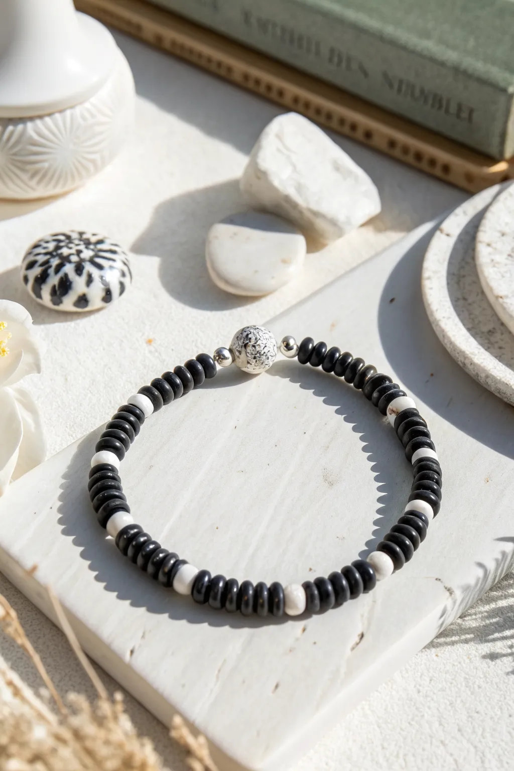 Black and white clay heishi bracelet with a bold graphic charm, minimalist and modern.