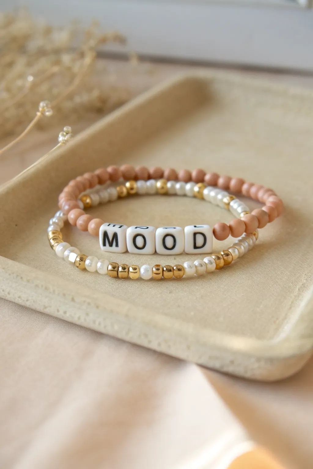 Tiny word bracelet stack in blush and sand tones, simple heishi beads with a cozy boho feel.