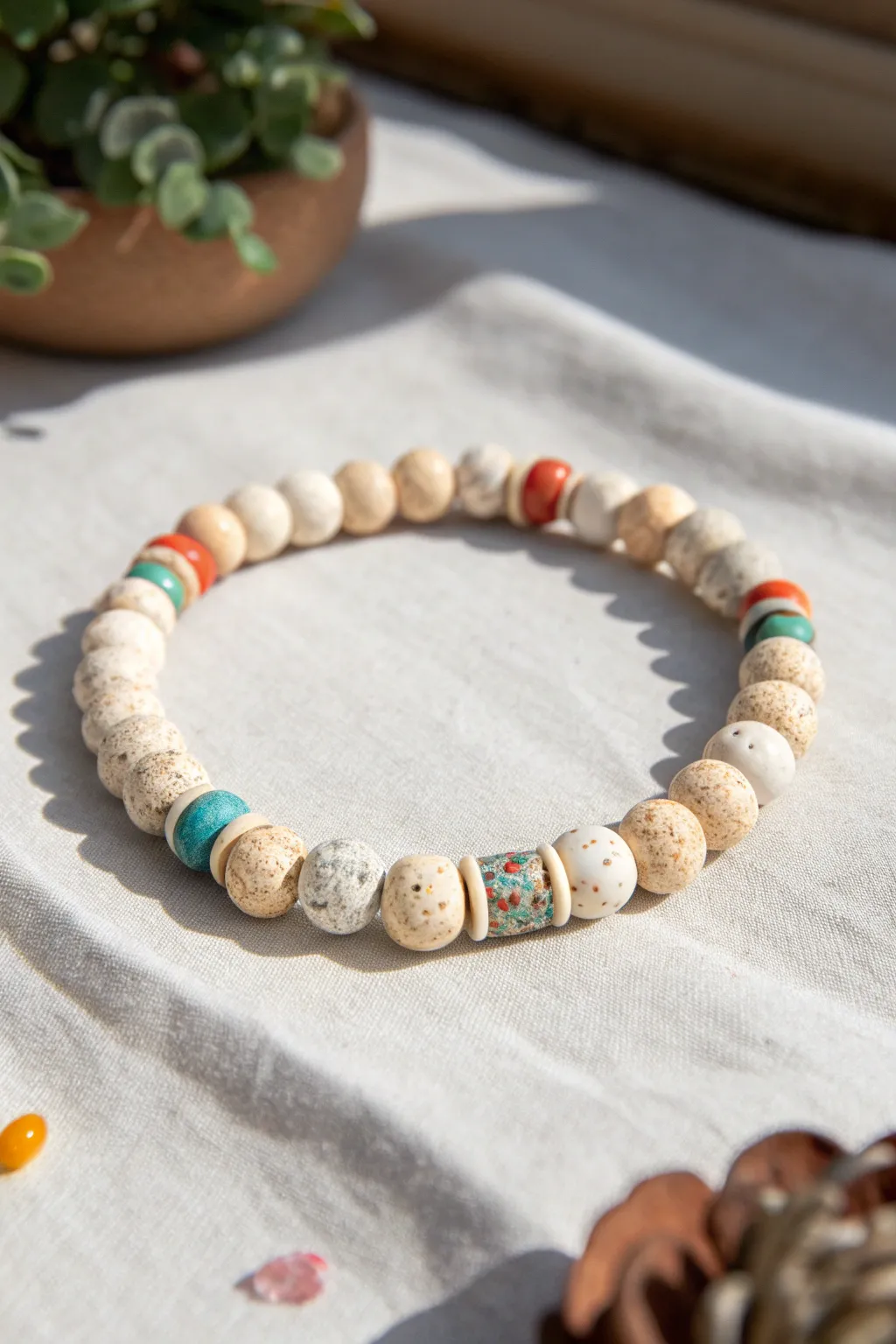 Speckled terrazzo clay bead bracelet in neutrals with tiny color confetti, styled in minimal flat lay.
