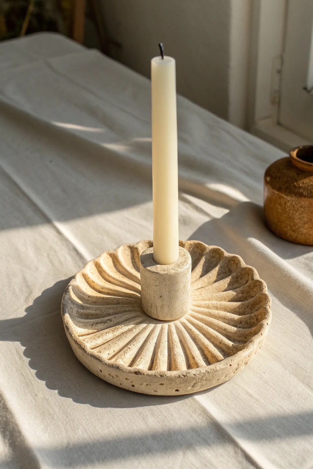 Fluted sunburst clay taper holder in warm evening light, highlighting handmade texture.