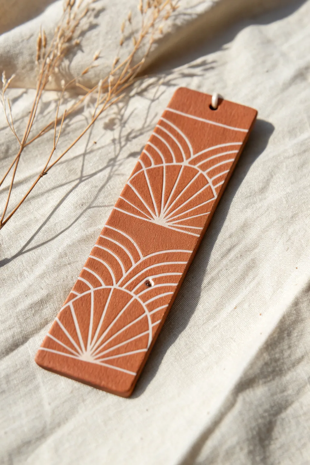 Terracotta bookmark with crisp white inlay linework, minimalist pattern with warm handmade texture