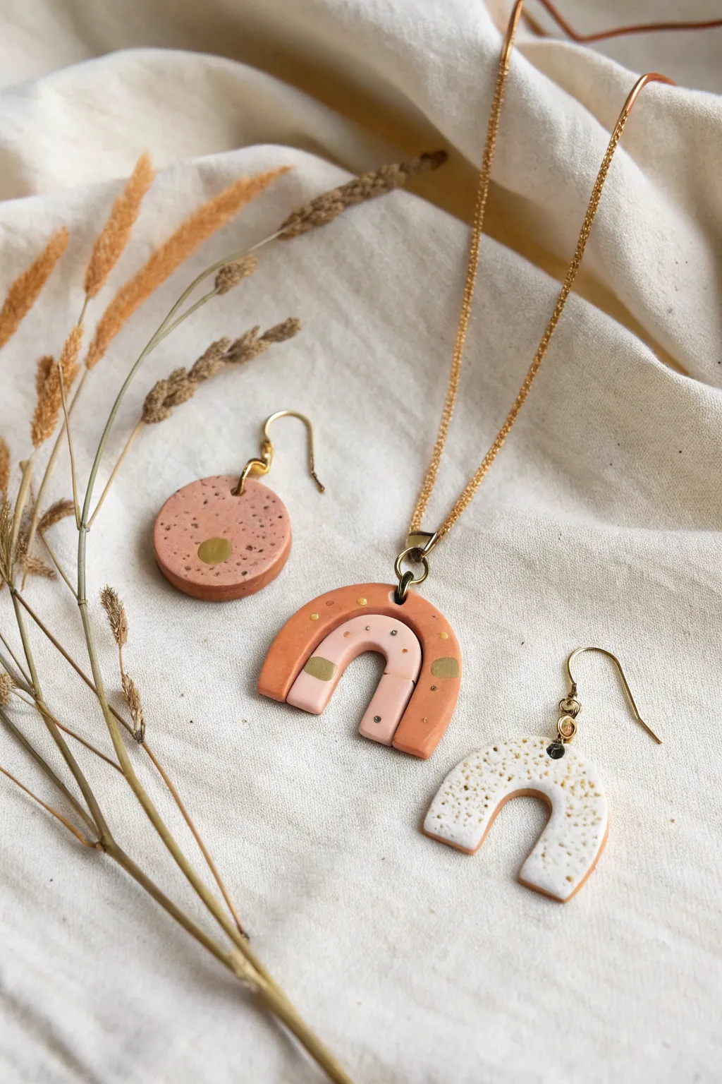 Minimal polymer clay jewelry capsule set in muted tones on linen, Scandinavian boho feel.