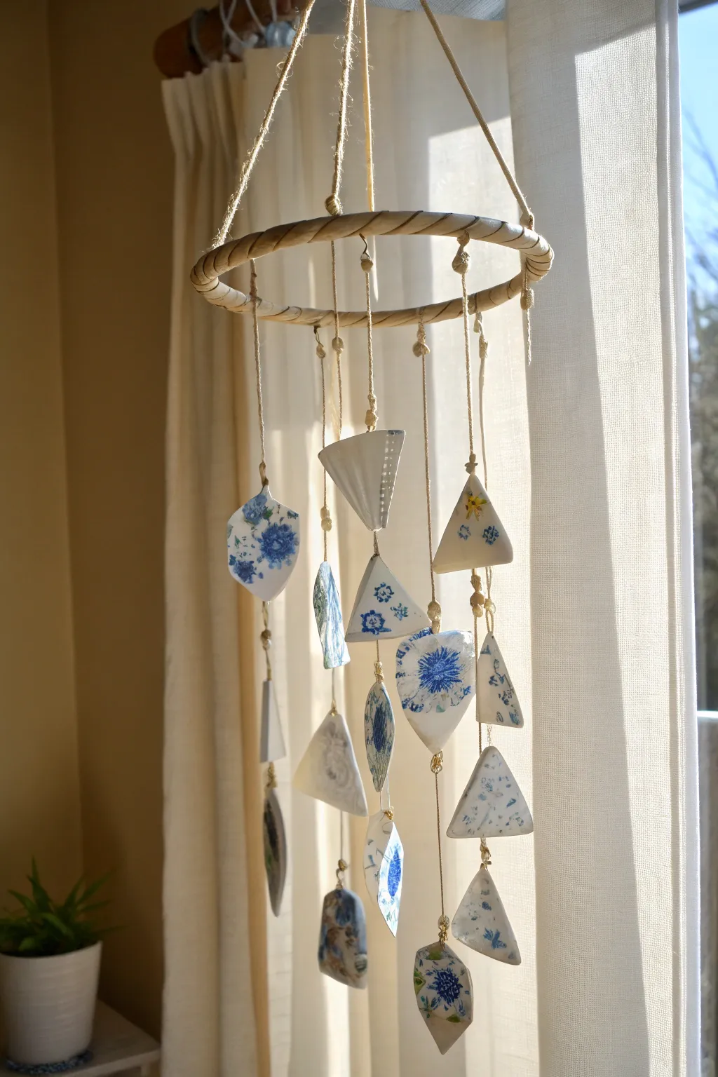 Vintage china plate wind chime suncatcher glowing softly in warm morning window light