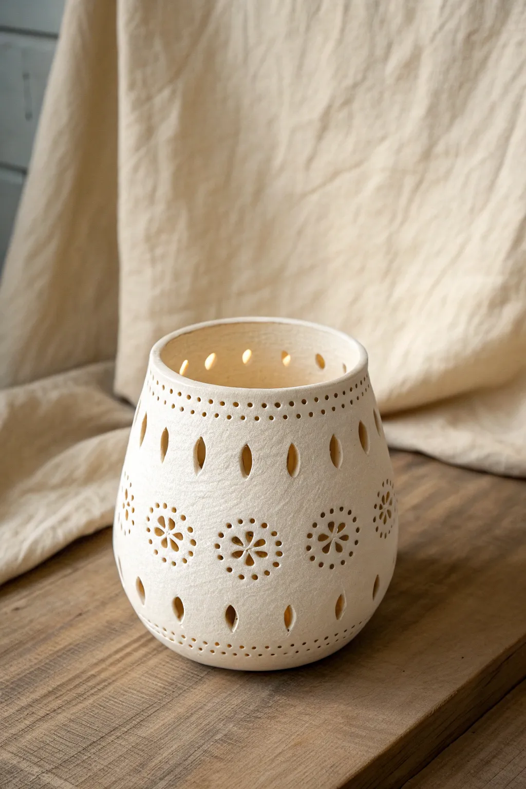 Peekaboo piercings turn a simple clay cup into a lantern of soft shadows and light.