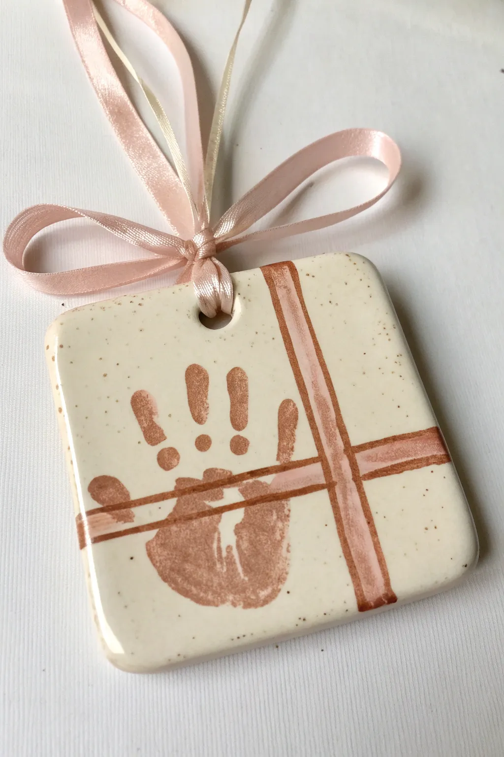 Sweet handprint present ornament with ribbon-wrap illusion, minimalist boho keepsake to hang.