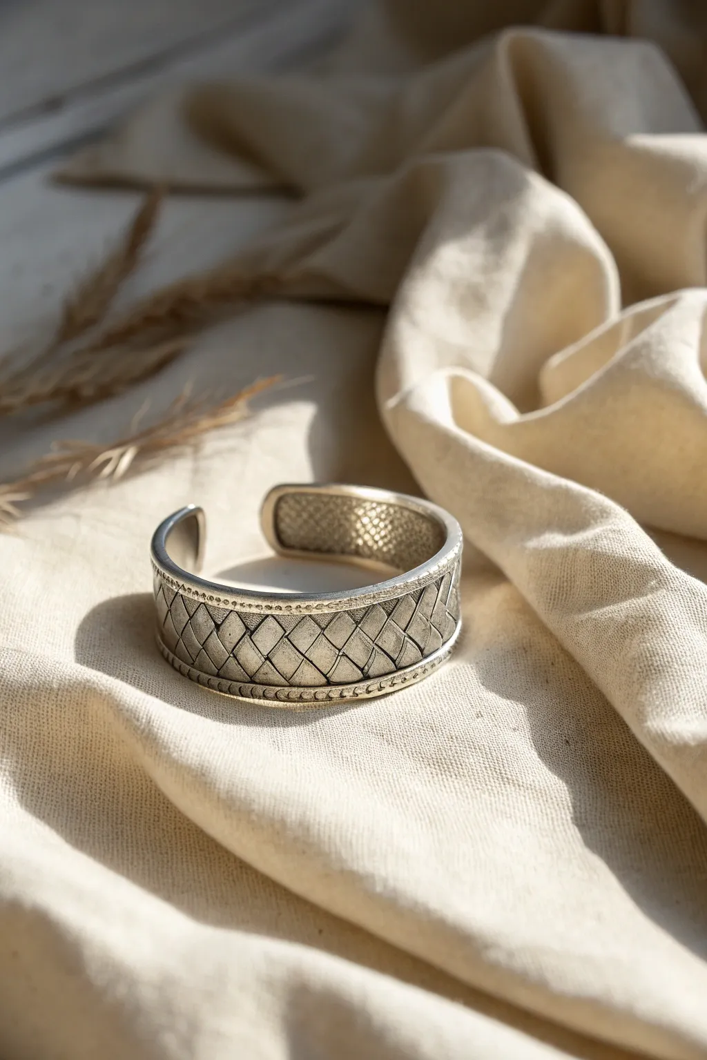 Woven metal clay cuff on neutral linen, minimalist Scandinavian style with a soft boho touch