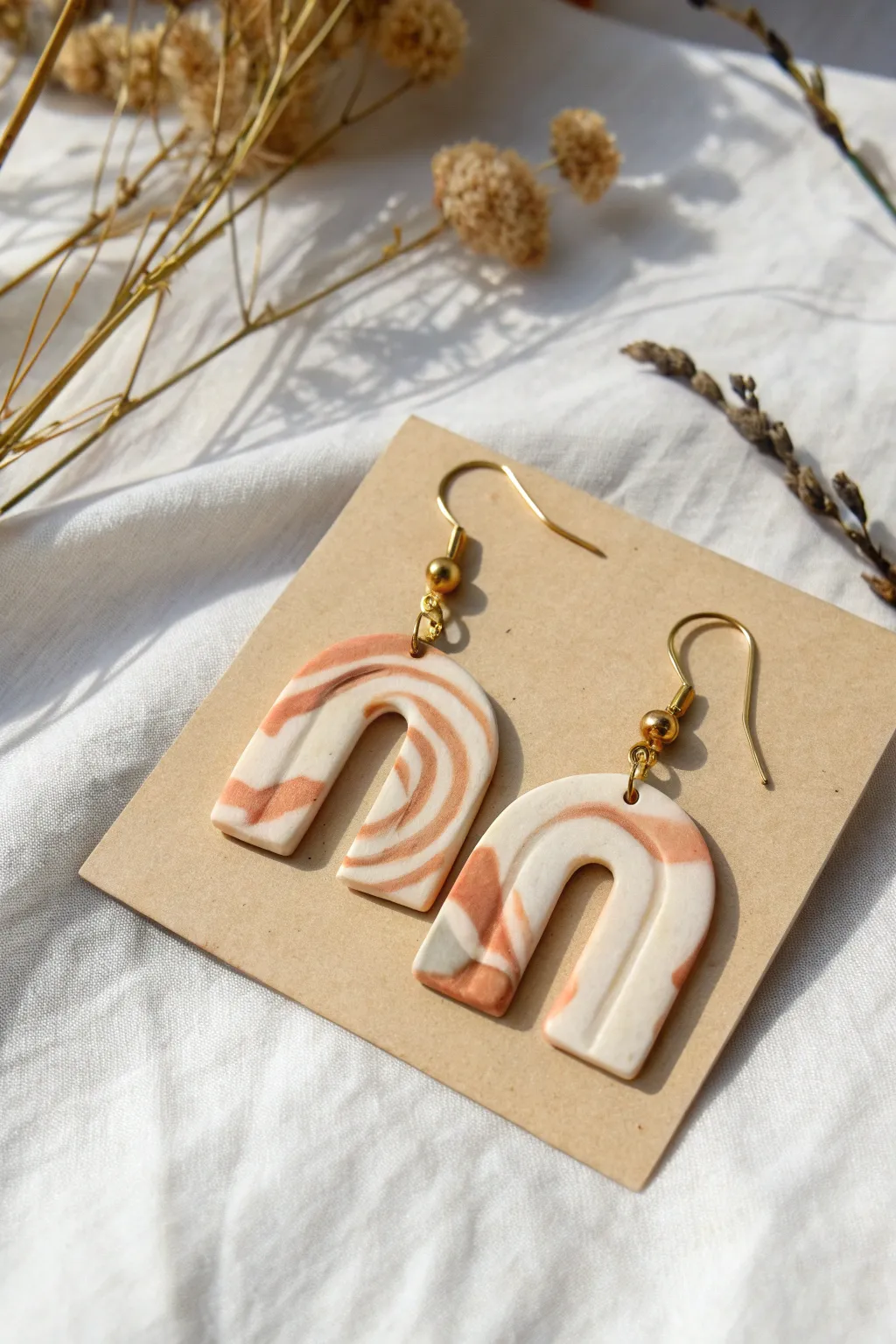 Minimal marbled clay arch earrings styled on linen for a modern, handmade Scandinavian look