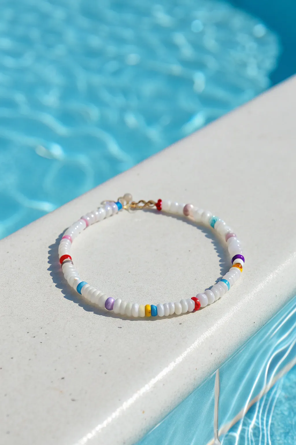 Confetti heishi bracelet on pool-blue backdrop, simple summer sparkle with handmade charm.