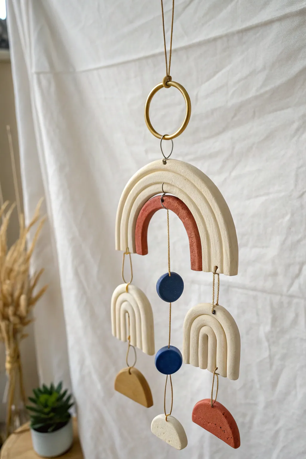 Minimalist air dry clay arch mobile in soft neutrals with a bold pop of cobalt