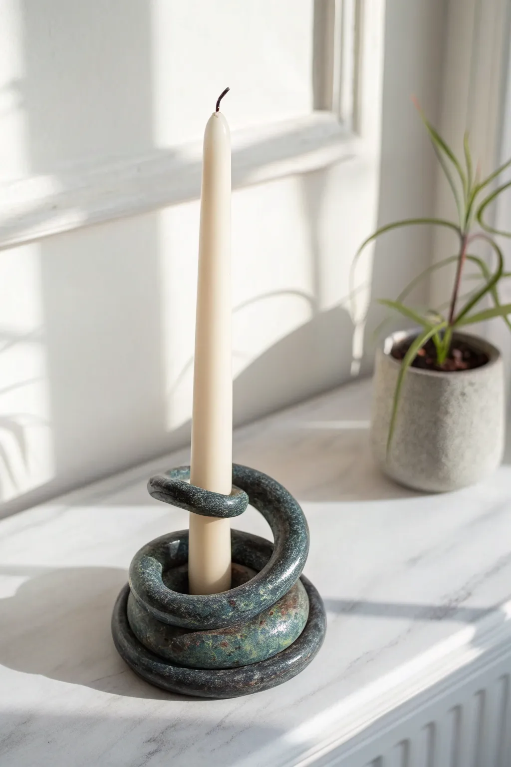 A bold coiled snake taper holder in deep charcoal, minimalist styling with striking contrast.