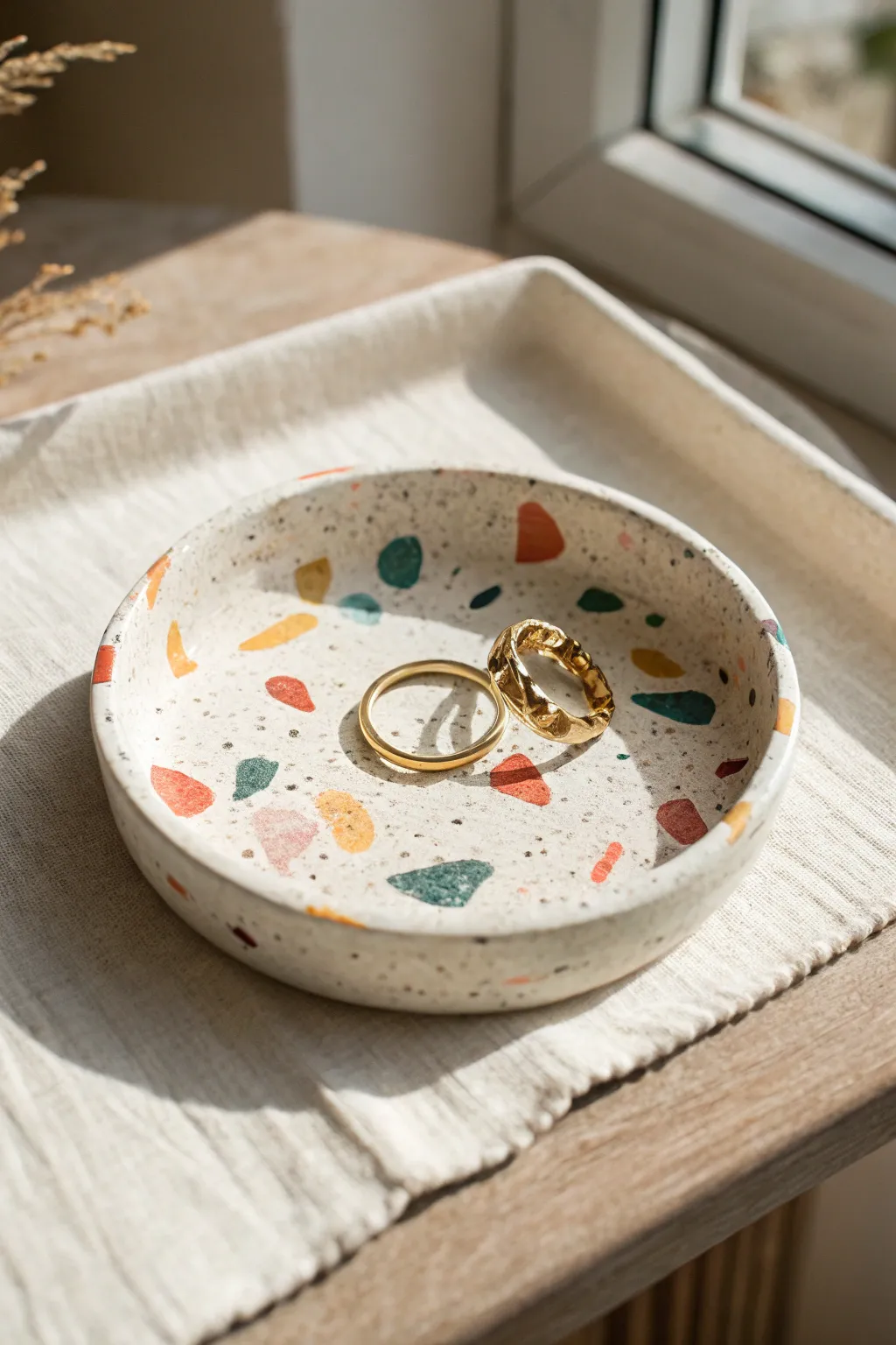 Terrazzo confetti air dry clay dish with bold flecks, styled simply with two rings