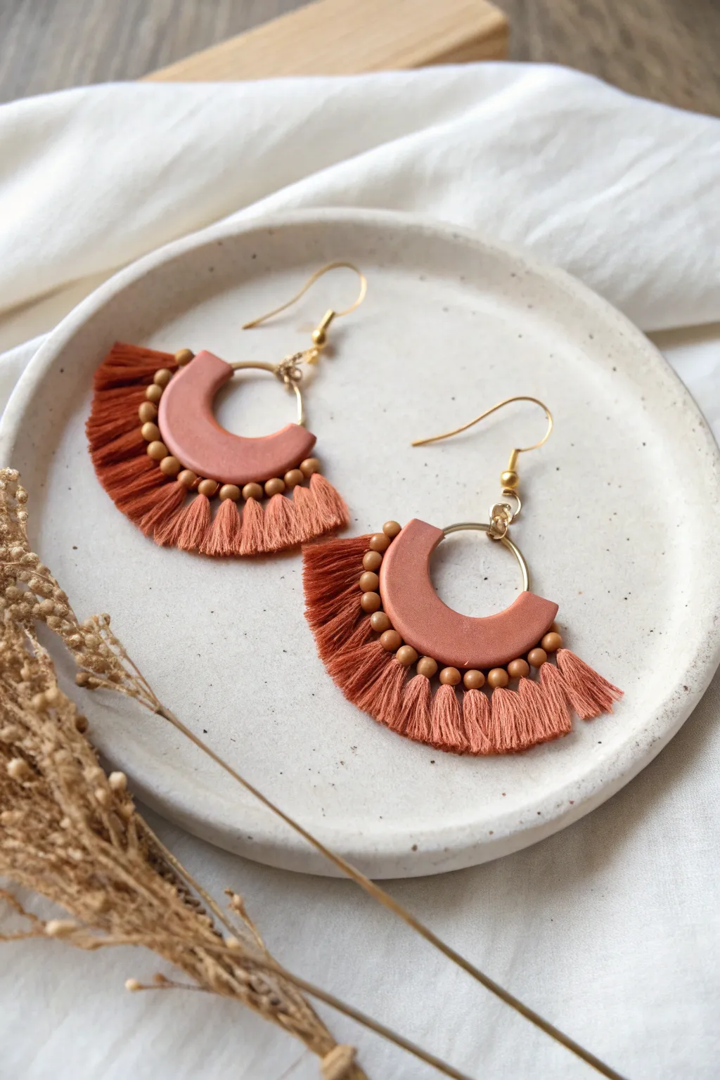 Mini bead fringe air dry clay earring in bold coral on a minimalist ceramic tray
