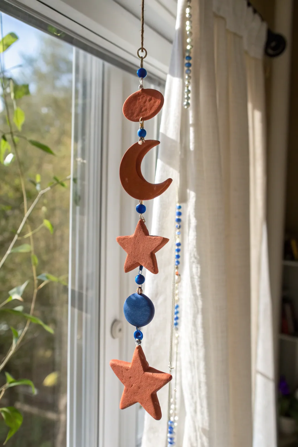 Bold clay suncatcher shapes glowing in a sunny window, minimal and dreamy for teen rooms