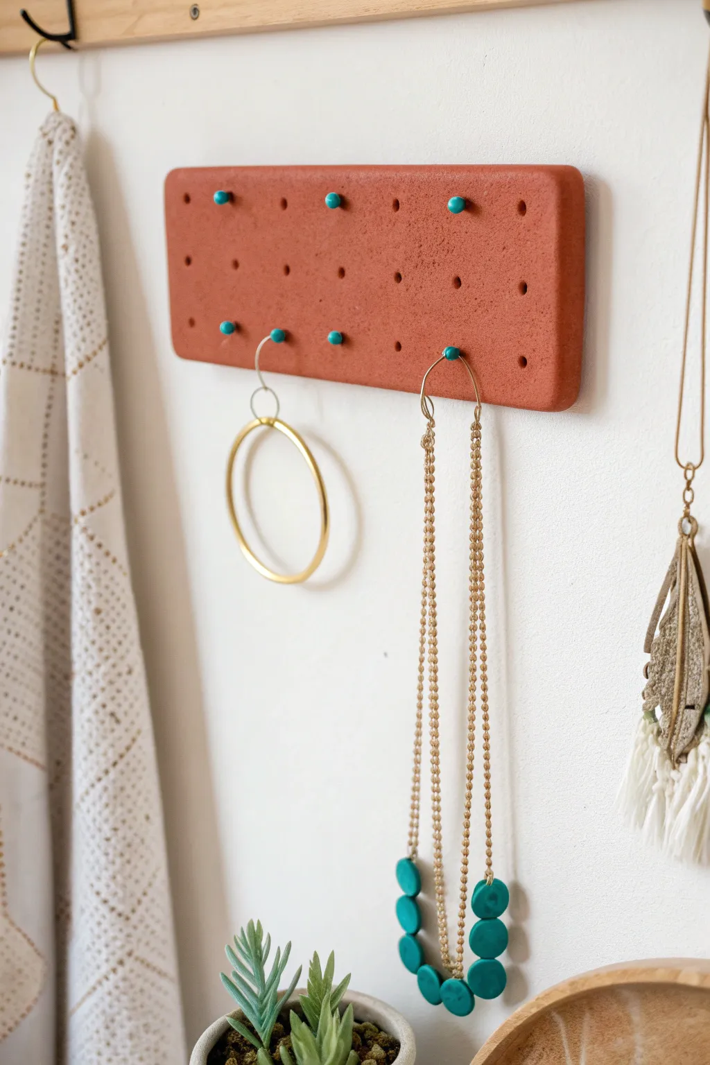 Minimal wall-mounted clay peg board with a few gold pieces for an easy, chic jewelry display.