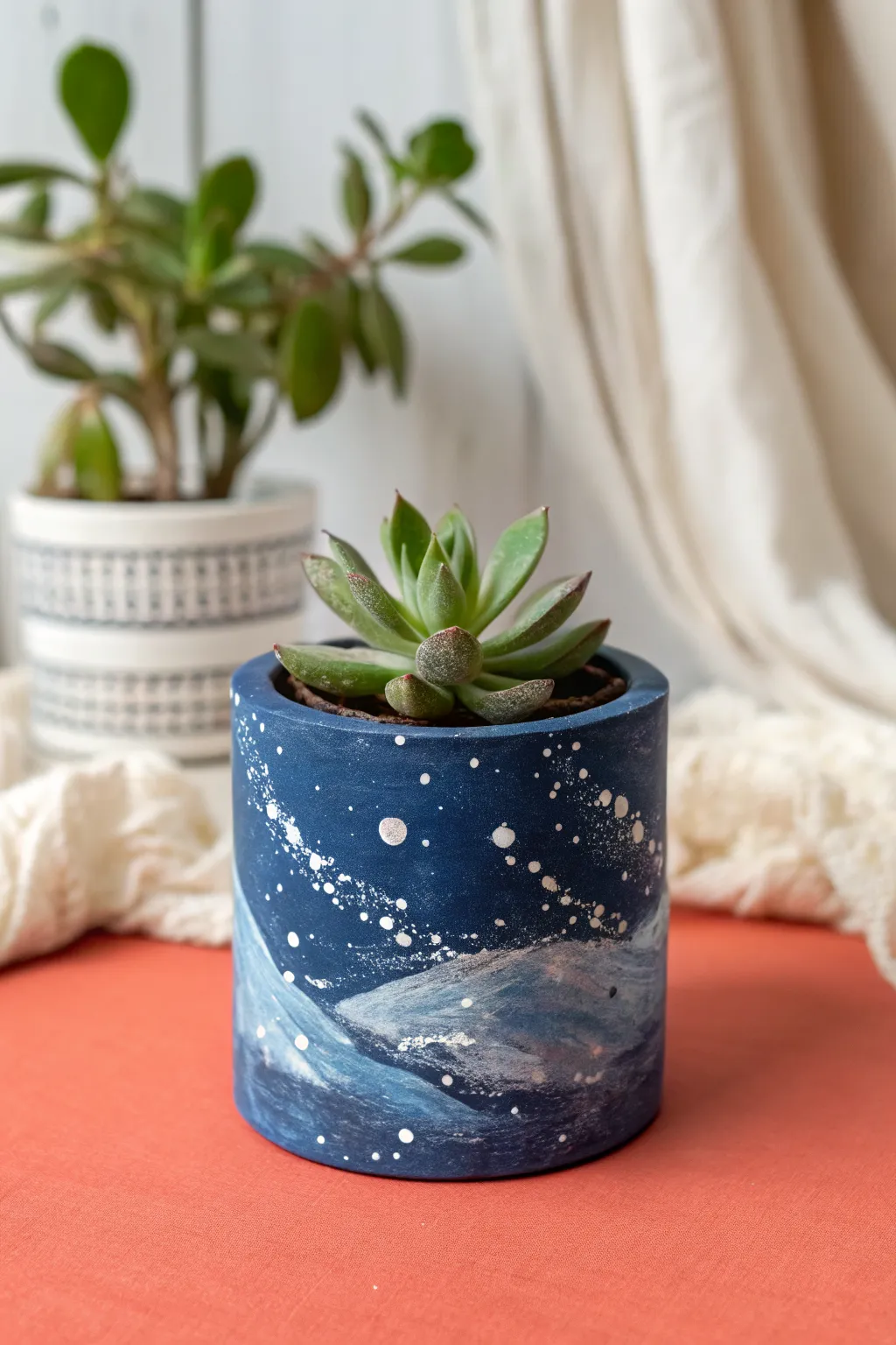 DIY-worthy blue galaxy air-dry clay planter cover with crisp white speckles on a coral tabletop.