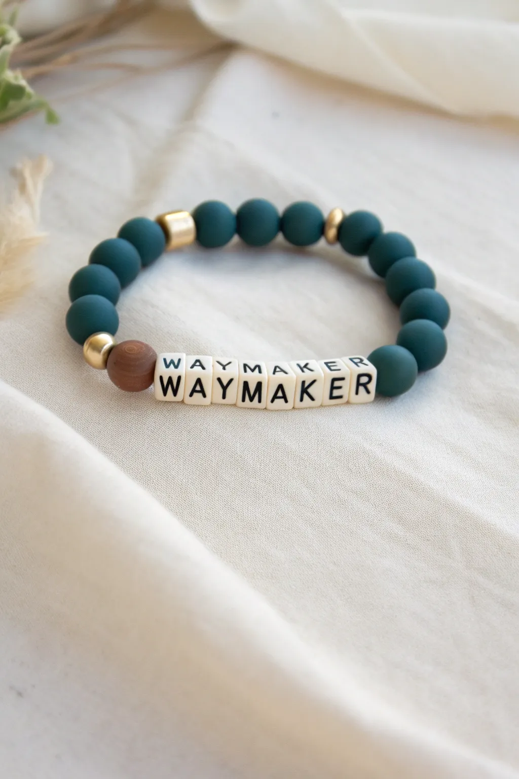 Deep teal and cream clay disc bracelet with gold spacers and Waymaker letter beads, serene and bold