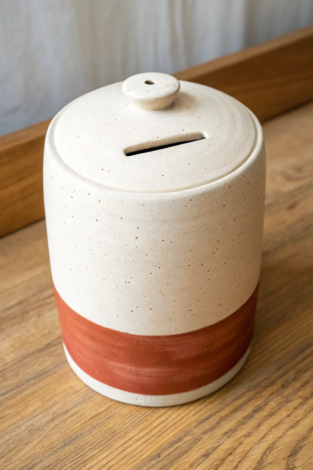 Minimal clay coin bank with a tidy removable stopper bottom, Scandinavian calm with bold color.