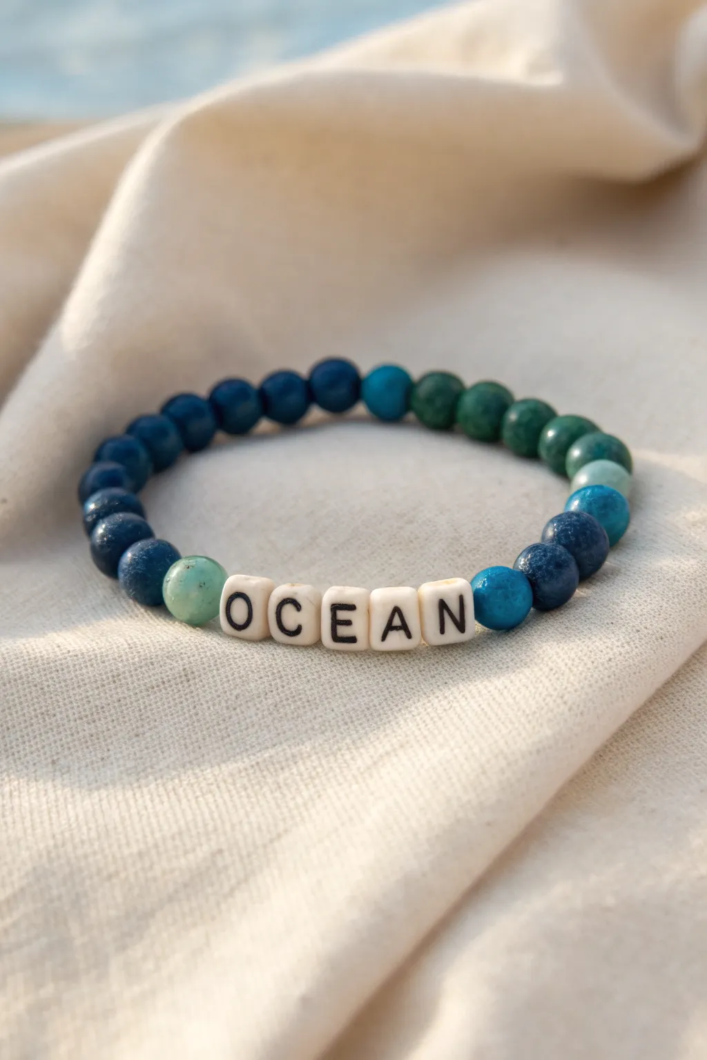 Sea-glass blues and greens spell OCEAN, a calm color-matched clay bead word bracelet.