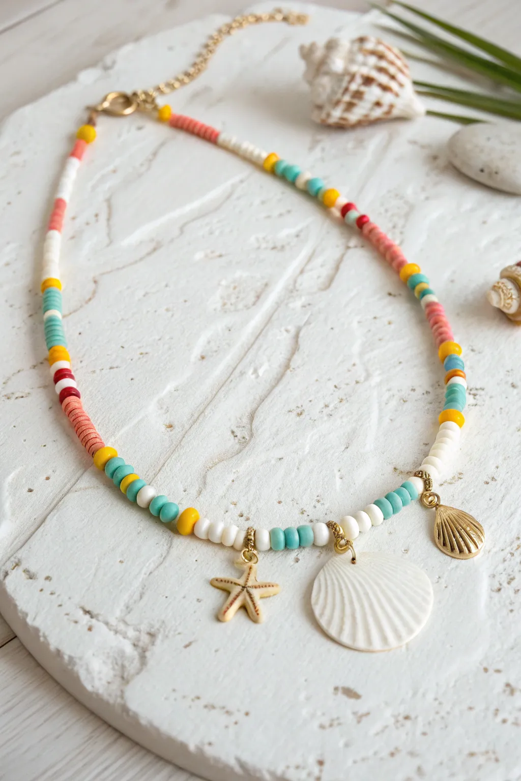 Beachy clay bead necklace with bold heishi colors and a sweet shell charm cluster drop.