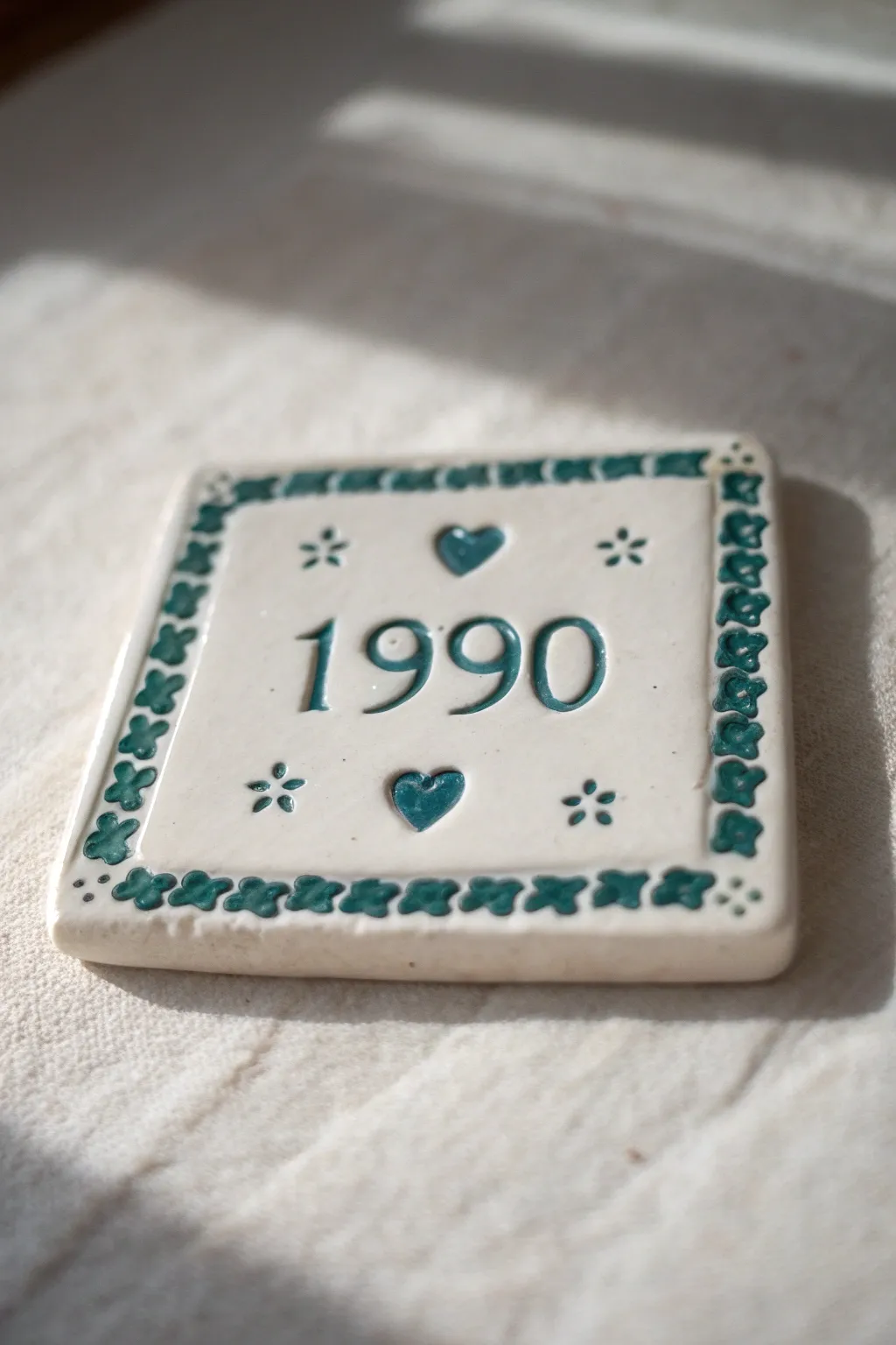 Milestone memory tile with an embossed year and sweet stamped icons, a timeless clay birthday gift.