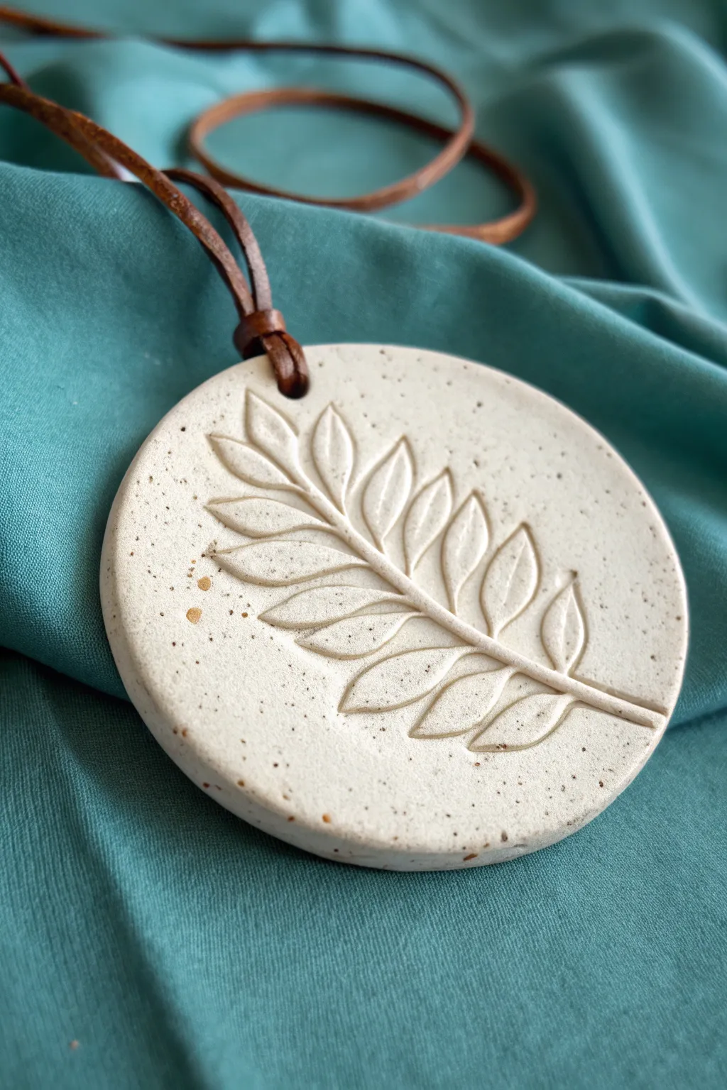 Simple relief clay medallion with a raised leaf design on a bold, minimalist backdrop